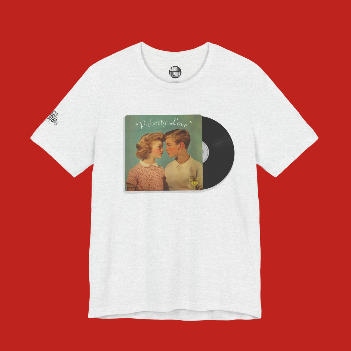 A white heather crewneck t-shirt featuring a graphic print of a vintage CD album cover titled 'Puberty Love' with a black vinyl record overlay, displayed on a clean white background.