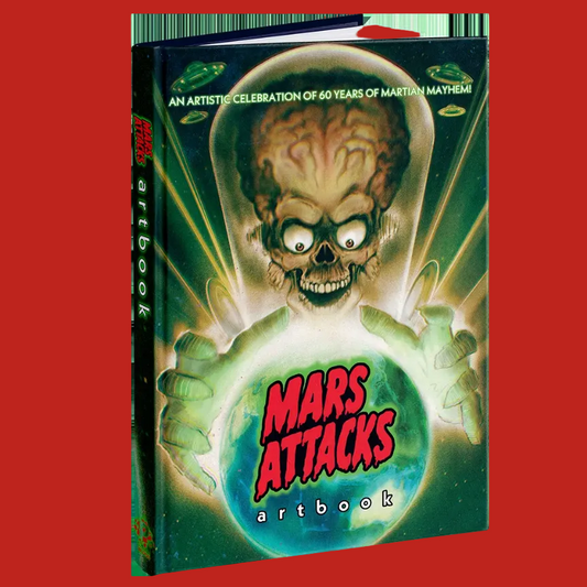 A hardcover artbook titled 'Mars Attacks' featuring a stylized alien skull in a spacesuit holding a glowing green planet against a starry space background. The spine and cover display the title and 'artbook' branding.