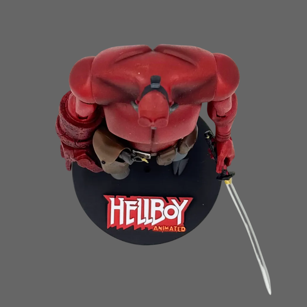 A Hellboy collectible figure posed on a black circular base with the Hellboy Animated logo, holding a silver sword against a plain white background.