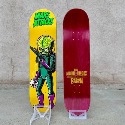 Mars Attacks skateboard Purple Boots skate deck.  Front and Back display. The art side has a bright yellow background with a green alien graphic and the words 'Mars Attacks. The back side lists the Topps, Atomic Toybox and Tim BAron logos.