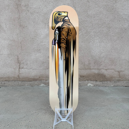A skateboard deck with a graphic print of a bald eagle holding a spear, displayed on a small white stand against a textured concrete wall and floor. Atomic Toybox
